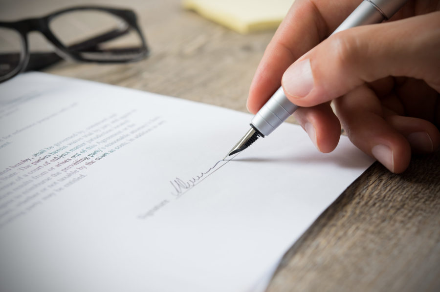 Close up of man's hand signing a contract to sell your business