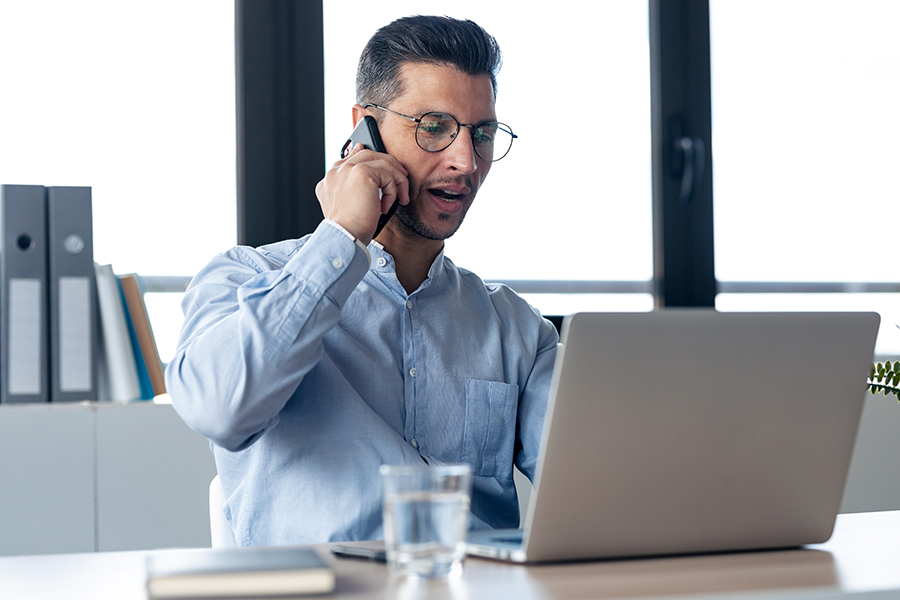 busy male entrepreneur talking on phone and working on laptop computer