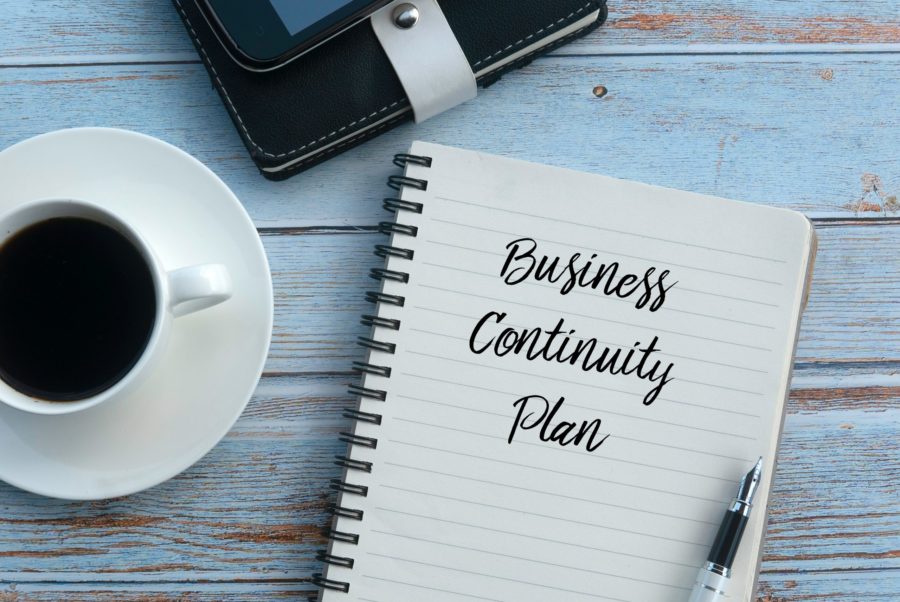 A spiral notebook with the words business continuity plan written on the page.