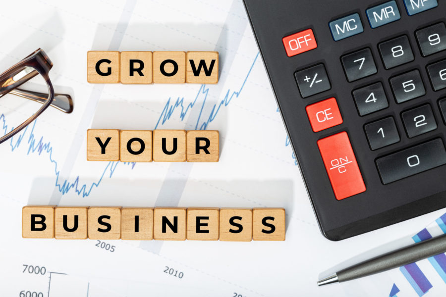 Wooden blocks write out Grow Your Business, calculator and printed chars