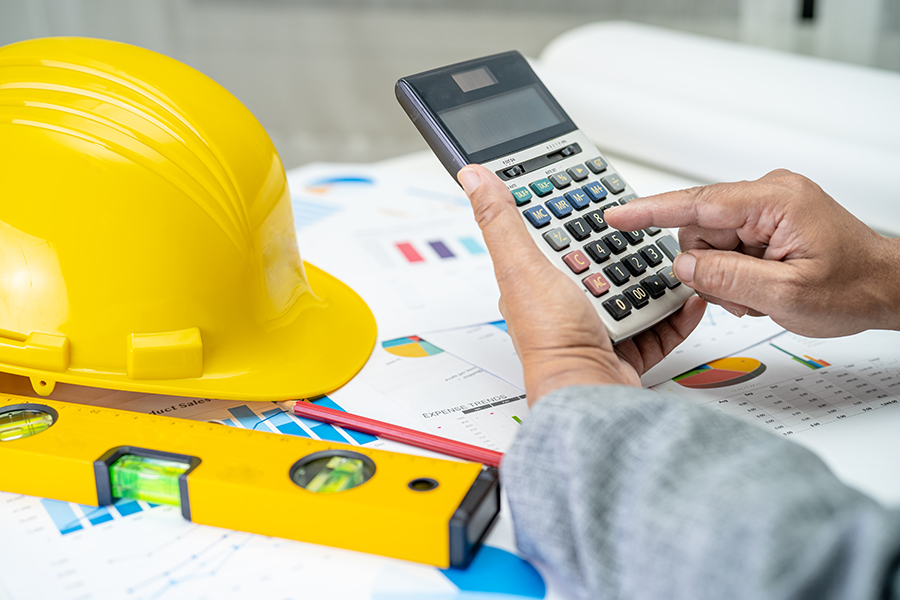 Hands use a calculator to determined construction deferred revenue